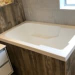 Nirvana deep soaking tub, corner installation, wood panel surround.